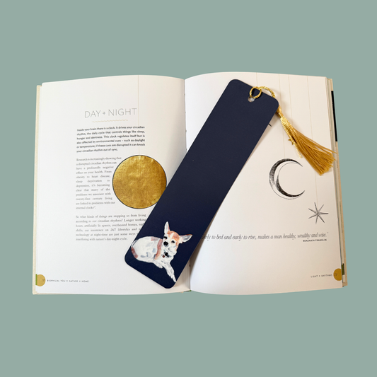 Navy blue bookmark with a Chihuahua illustration on an open book with celestial designs.