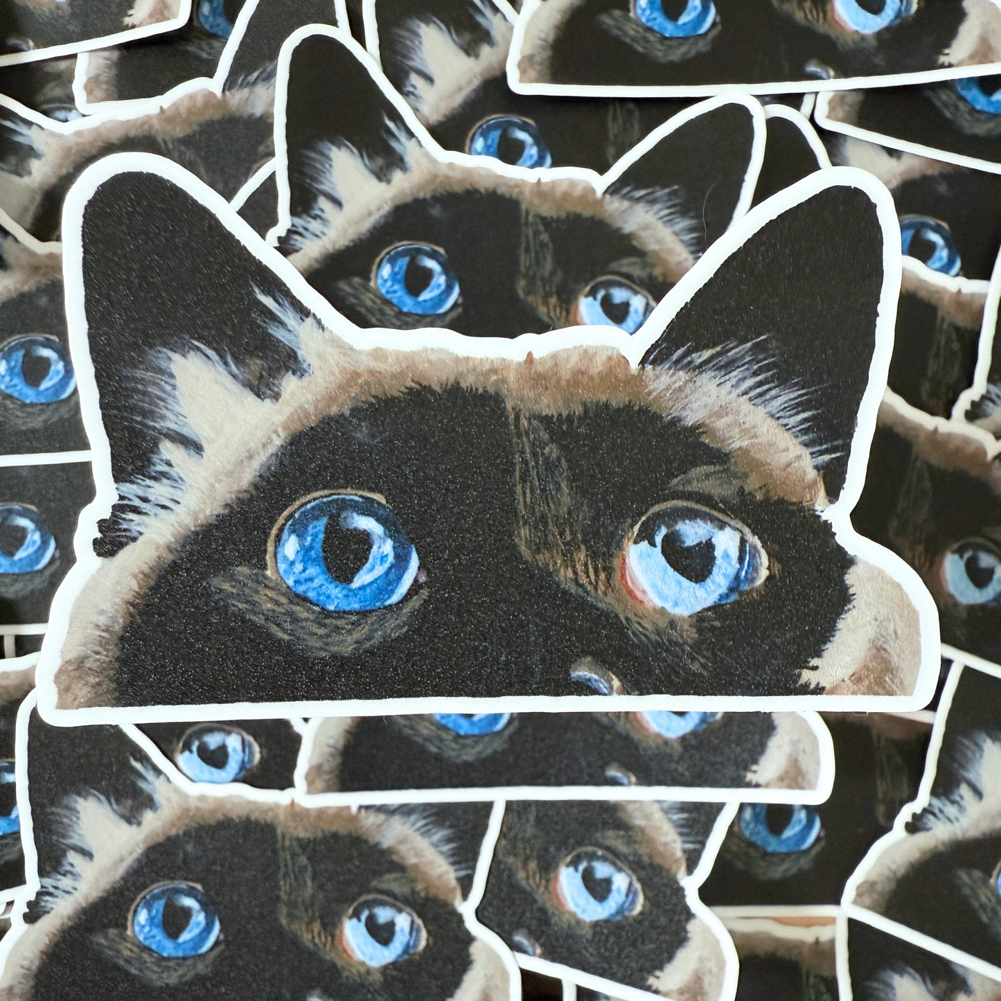 Stack of stickers with a cat face design featuring blue eyes.