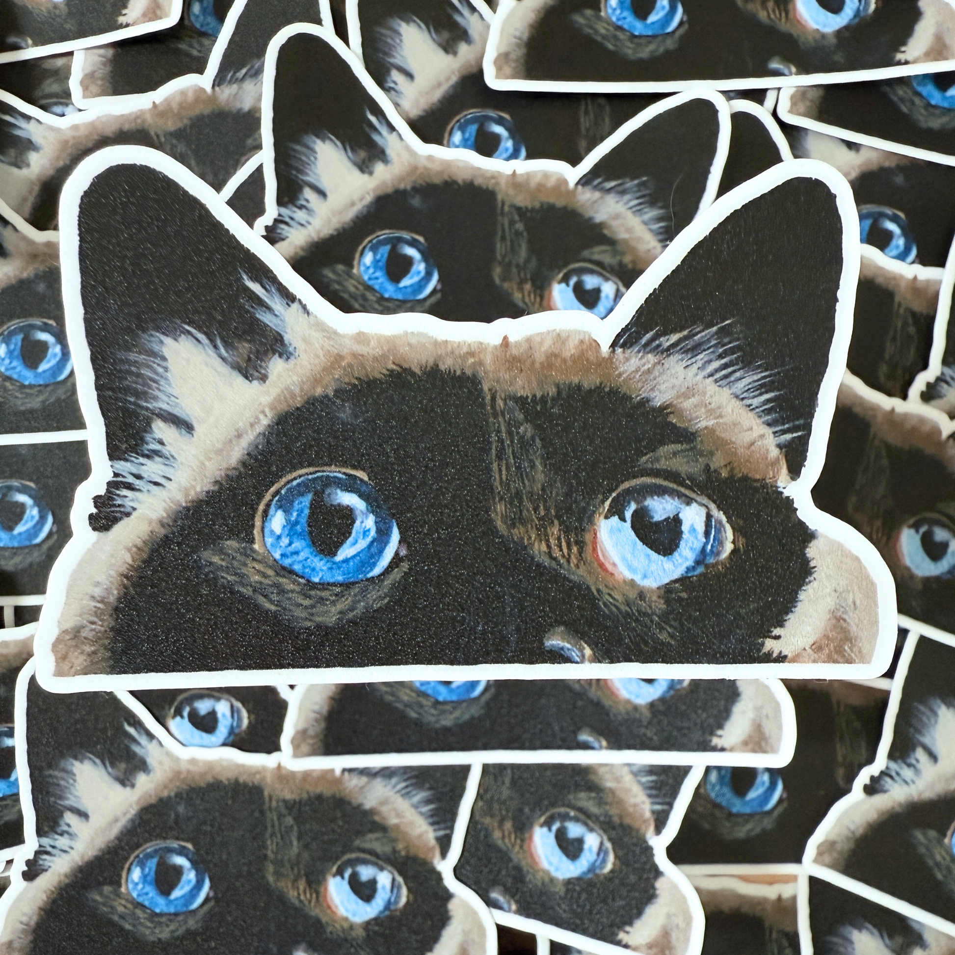 Stack of stickers with a cat face design featuring blue eyes.